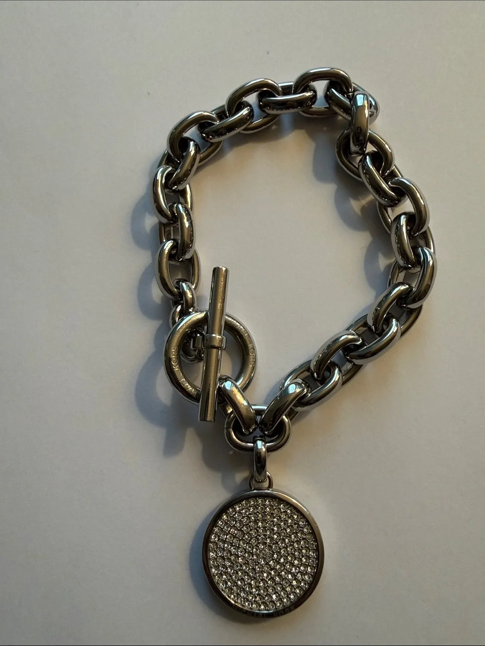 Michael Kors Silver-tone Toggle Bracelet with Dual Sided Logo Charm.